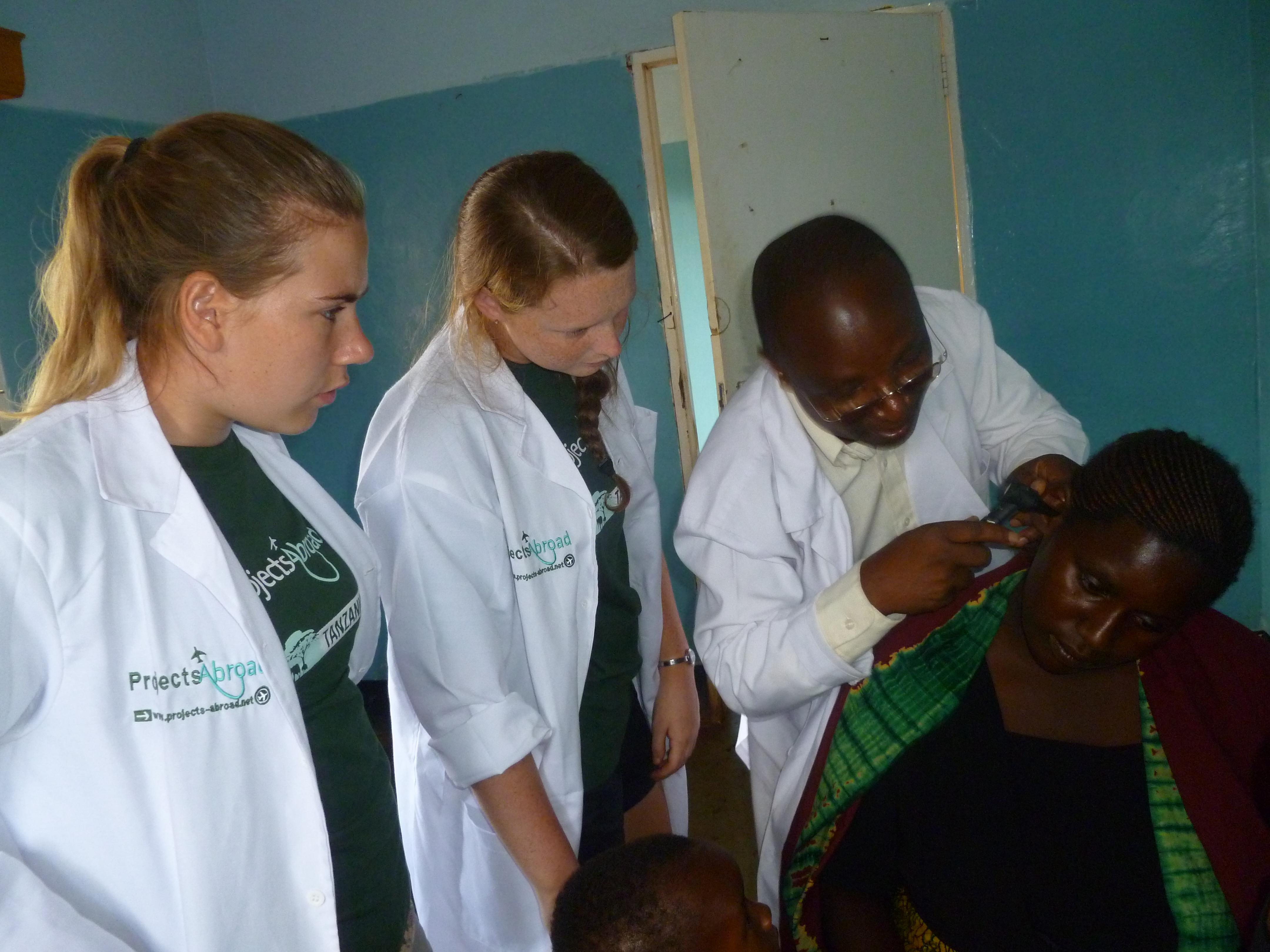 Projects Abroad interns observe a doctor's examination on our medical internship for teenagers in Tanzania High school students sit in on a consultation during their medical internship in Tanzania